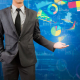A man in a suit hold out his hand, where projections of various data visualizations hover over his hand.
